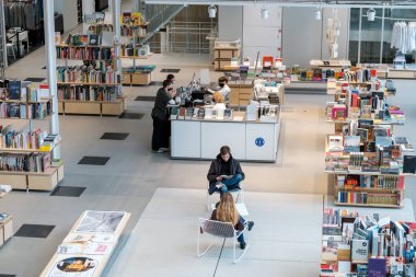 Vilnius, Litvanya - 10 Ekim 2022: Yukarıdan öğrenciler kitap okuyor ve modern kütüphanede vakit geçirirken kütüphanecilerle konuşuyor