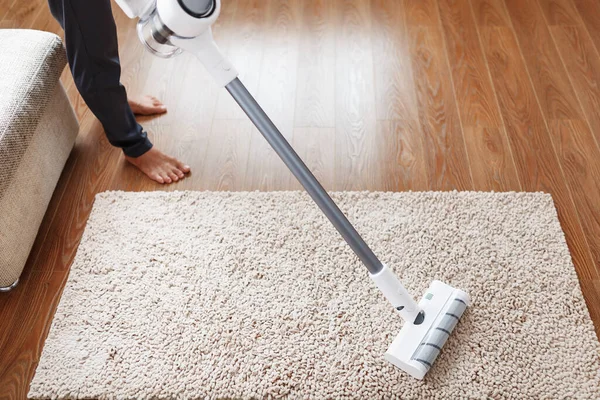 A cordless vacuum cleaner cleans the carpet in the living room with the bottom of the legs. Modern technologies for cleaning the house. turbo brush