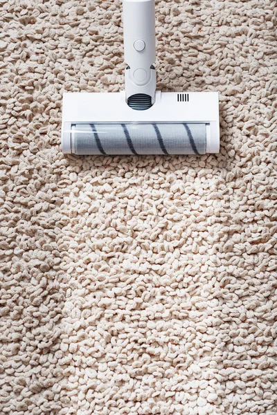 The turbo brush of a cordless vacuum cleaner cleans the carpet in the house in close-up. Modern technologies for cleaning.