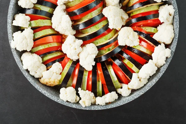 Ratatouille of freshly cut vegetables in a frying pan on a dark background . Traditional French vegetable dish