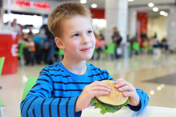 Malý chlapec jíst hamburger — Stock fotografie