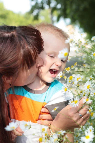 Ребенок, нюхающий цветы вместе с матерью — стоковое фото