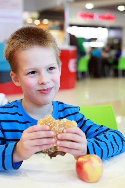 Jongen eten hamburger en apple — Stockfoto