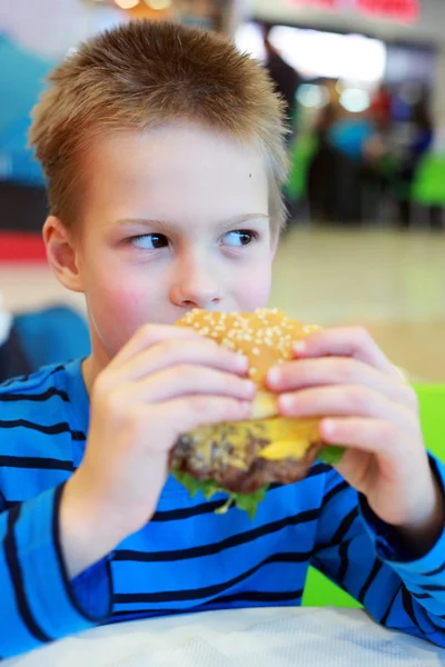 Маленький мальчик ест бургер — стоковое фото