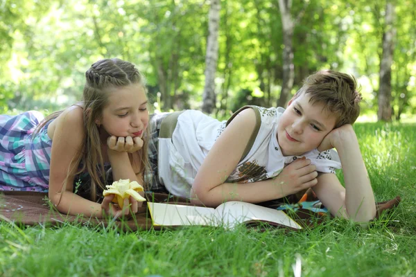 Flicka och pojke läser en bok — Stockfoto