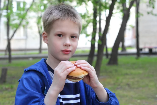 Junge isst Hamburger im Park — Stockfoto