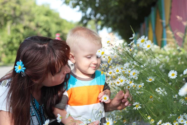 Child smelling the flowers with his mother — Stock Photo, Image