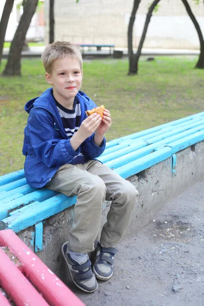 公園でハンバーガーを食べる少年 — ストック写真