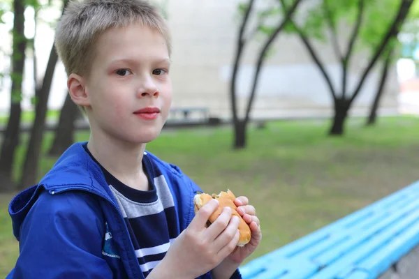 公園でハンバーガーを食べる少年 — ストック写真