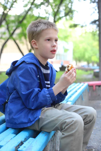 Pojken äta hamburgare i parken — Stockfoto