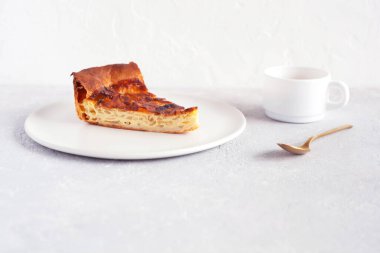 Tabakta bir dilim soğanlı turta, bir fincan kahve ve gri arka planda kaşık, yan görüş.