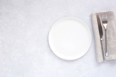 boş, beyaz yuvarlak tabak ve gümüş çatal bıçak takımı açık gri masa arkaplanı, üst görünüm, boşluk kopyala