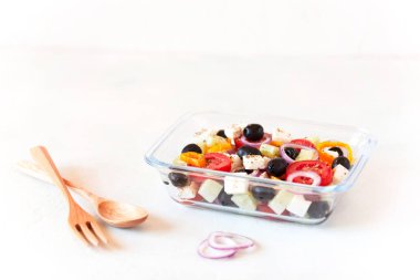 Yunan salatasıyla beslenme çantası, yeniden kullanılabilir cam kap, ahşap çatal bıçak, beyaz arka plan, yan görüş
