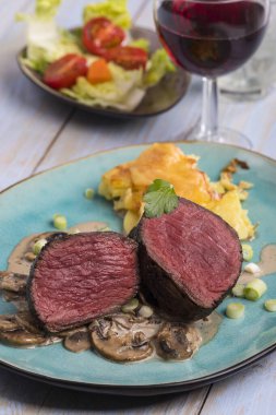 Bir tabakta dilimlenmiş biftek ve patates graten.