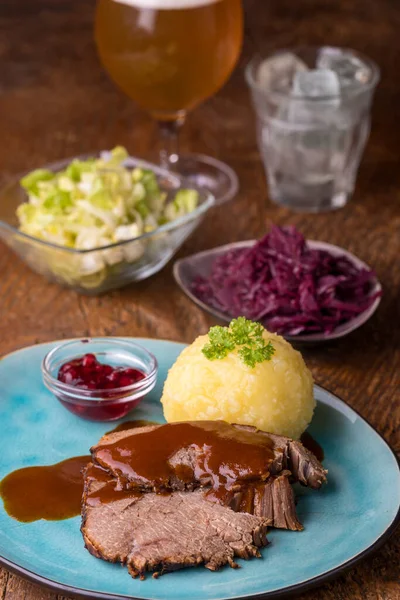 Alman sauerbraten ve tahtanın üzerinde patates köftesi.