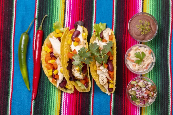 three mexican tacos on colourful cloth