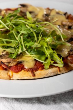 Arugula kaplı bir tabakta pizza