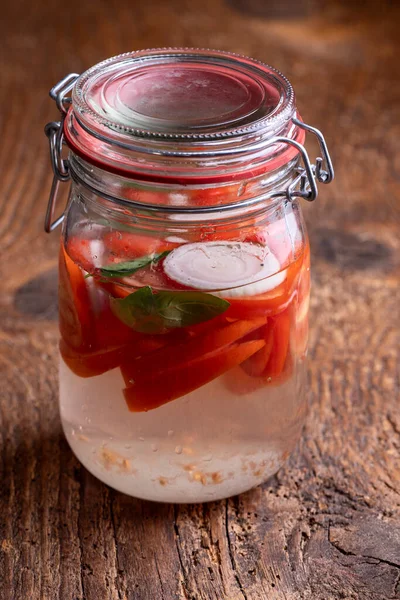 fermenting tomatoes in a jar on wood