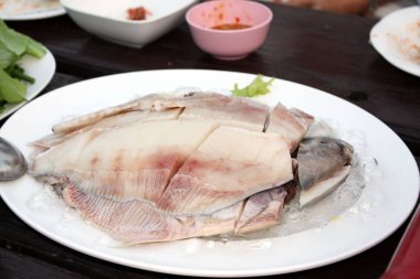Taze gri pomfret, buzla kaplı beyaz bir tabakta düzenlenmiş gümüş renginde pomfret balığı. Restorandaki ahşap masada, Shabu tenceresi için hazırlan. Seçici odak.
