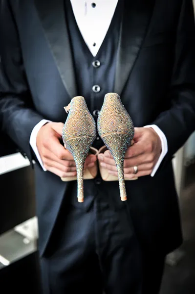 Groom holding bridal shoes — Stock Photo, Image