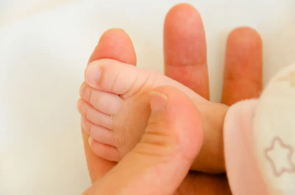 Der Fuß eines Babys in der Hand ihres Vaters — Stockfoto