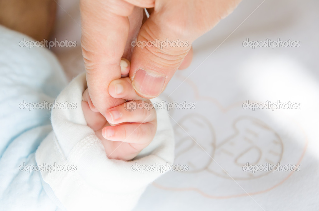 Holding hands of the baby and her father