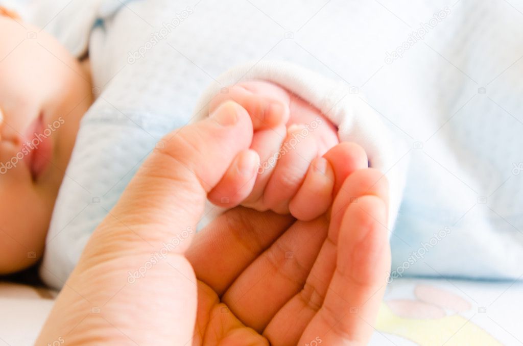 Holding hands of the baby and her father