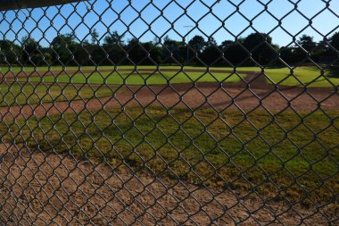 A baseball field shot through the fence in the early morning. clipart