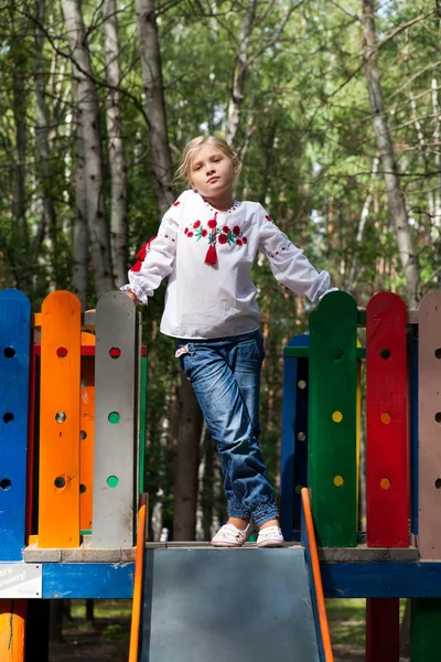 Девочка на детской площадке с различными аттракционами — стоковое фото