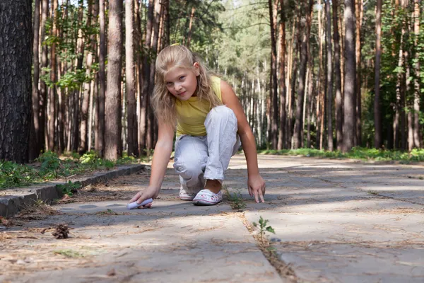 Young girl is drawing on the concrete ground — Stock Photo, Image