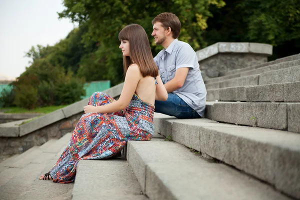 Couple sitting on stairs on green background — Stock Photo, Image