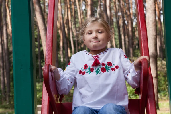 Ребенок в украинской рубашке на качелях — стоковое фото