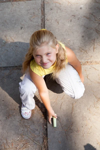 Young girl is drawing on the concrete ground — Stock Photo, Image