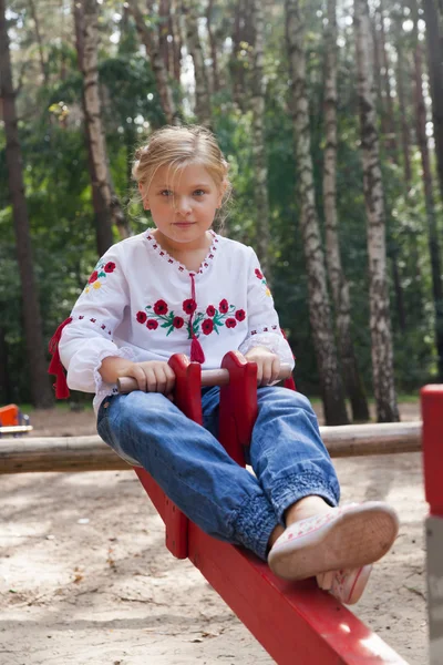 Дівчина на дитячому майданчику з різними атракціонами — стокове фото