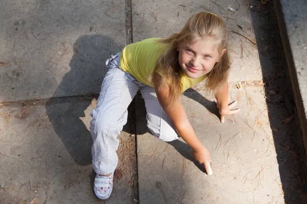 Giovane ragazza sta disegnando sul terreno di cemento — Foto Stock