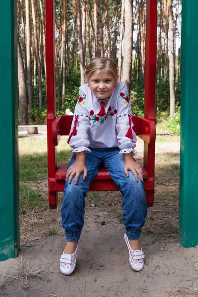 Niño en camisa de estilo ucraniano en un columpio — Foto de Stock