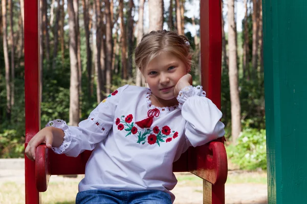 Child in Ukrainian style shirt on a swing — Stock Photo, Image