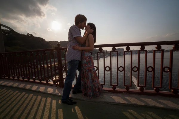 Casal abraçando e beijando em uma ponte — Fotografia de Stock