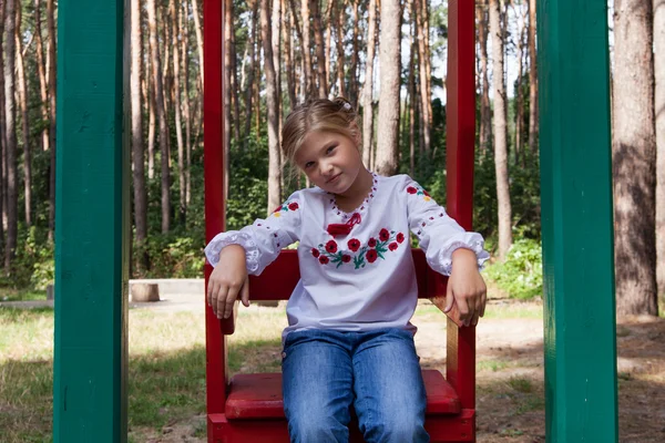 Child in Ukrainian style shirt on a swing — Stock Photo, Image