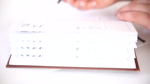 Man schrijven informatie in zakelijke agenda boek — Stockvideo