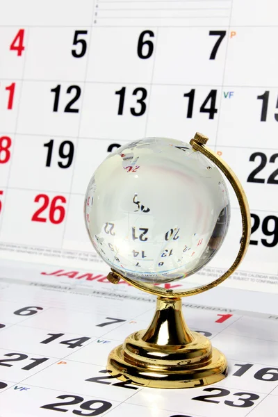 Стеклянный глобус на страницах календаря — стоковое фото