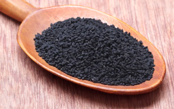 Nigella o comino negro en una cuchara de madera — Foto de Stock