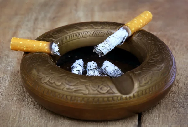 Burning cigarette on an old ashtray — Stock Photo, Image