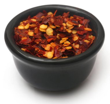 Siyah kasede ezilmiş biberler beyaz arka planda