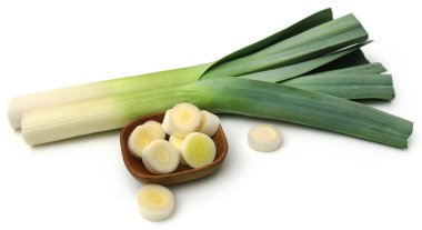 Beyaz arka planda bir kasede doğranmış taze pırasa sapı.