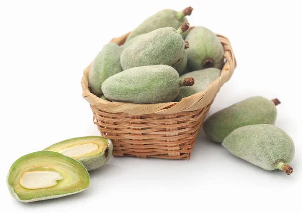 Green almond in basket over white background