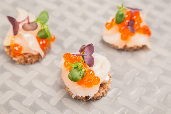 Salmon eggs, fish, and herbs canapes — Stock Photo, Image