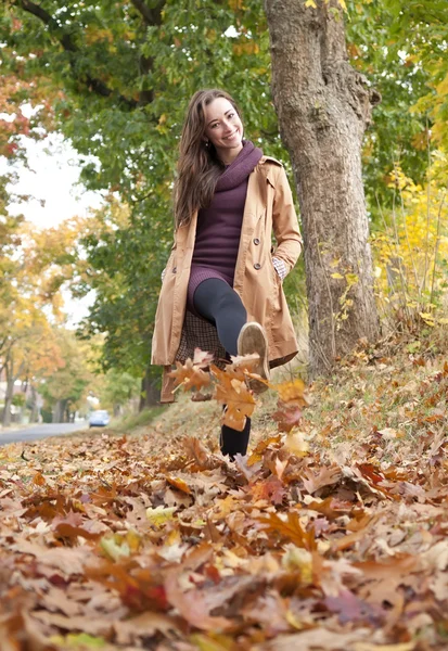 Mulher caminha em folhas de outono — Fotografia de Stock