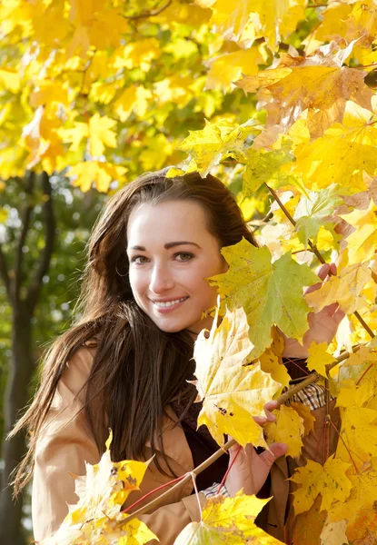 Vrouw ziet er door middel van gele bladeren — Stockfoto