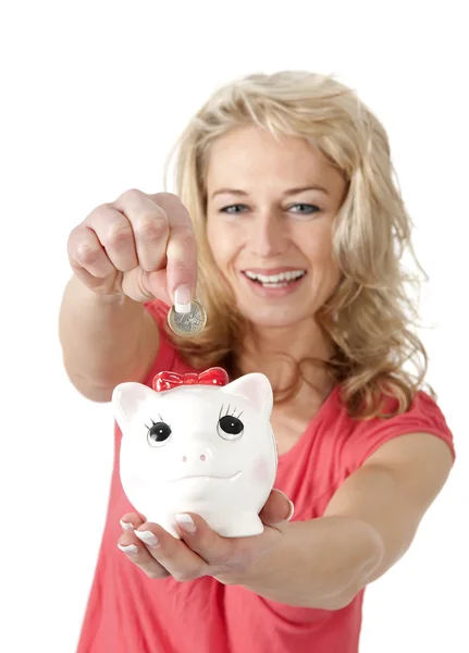 Sorrindo mulher colocando moeda de dinheiro no mealheiro — Fotografia de Stock